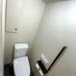 LIXILアメージュ便器のすっきりとしたシルエットと、足元の落ち着いたダークグレー床が美しい、トイレリフォーム後の見下ろしアングル。