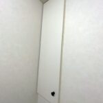 有限会社パイプラインの自社大工が造作したトイレの壁面埋込収納用目隠し扉。マットホワイトの扉に黒のアイアンつまみを取り付けたスタイリッシュなデザイン。