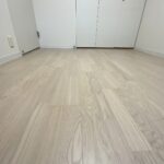 ペールグレーフローリングの質感と壁と同色塗装されたクローゼット扉の足元。